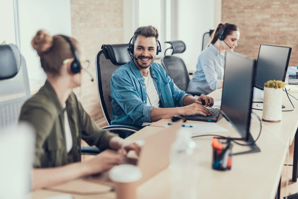 Happy male worker is sitting in the call center