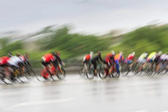 Group of colorful racing cyclists on the city roadway, day, abstract, motion blurred background with copy space. sport, health and activity concept