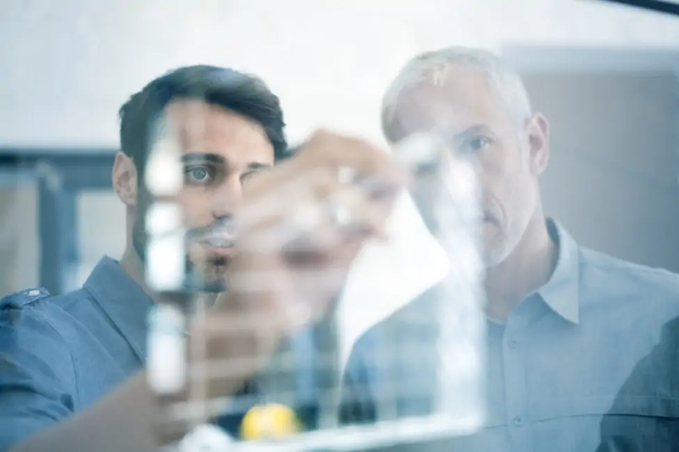 Businessmen making plan on glass wall in office
