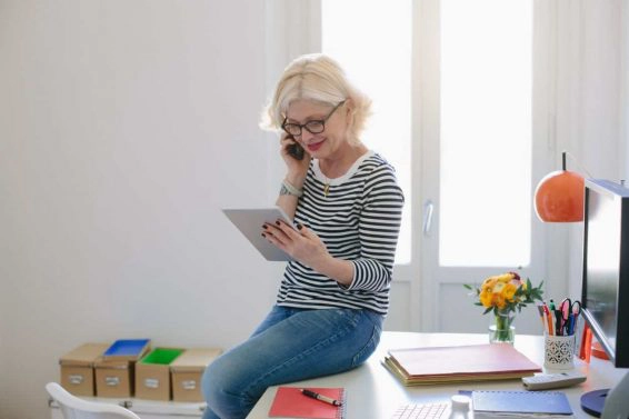 Mature woman at home using digital tablet and talking on phone
