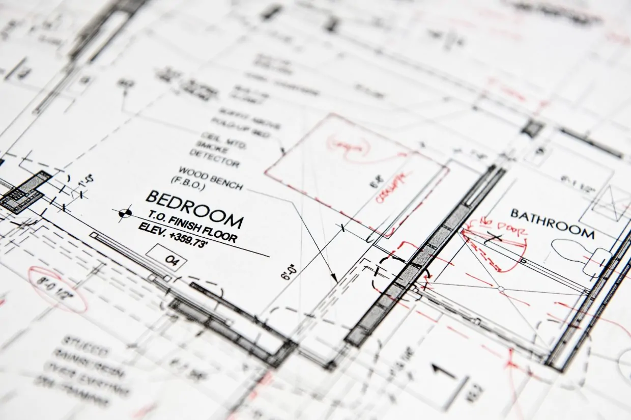 Closeup of a blue print, architects drawing with red pen alterations, details of a bedroom and bathroom in a new home.