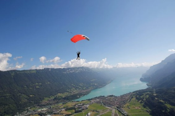 Male sky diver with parachute over lake, interlaken, berne, switzerland