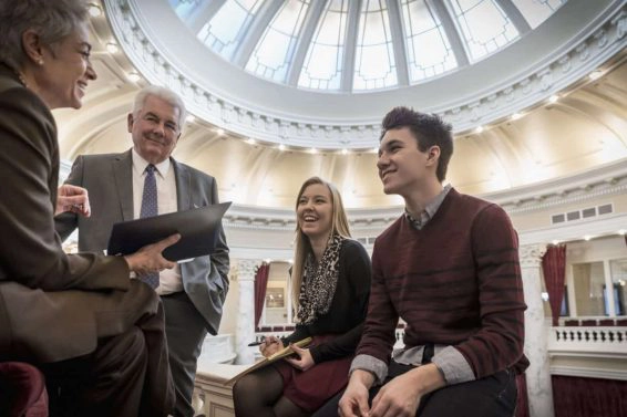Caucasian teenagers talking to politicians in capitol building
