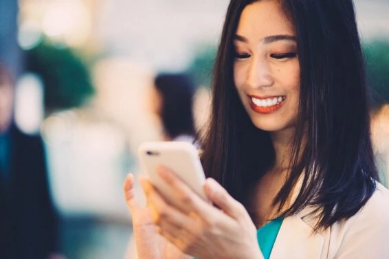 Smiling asian woman texting in the city