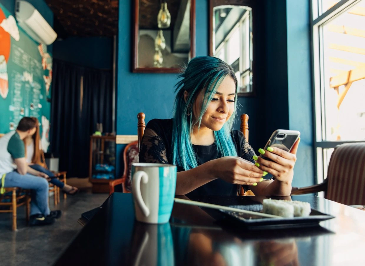 Hispanic woman using phone at lunch