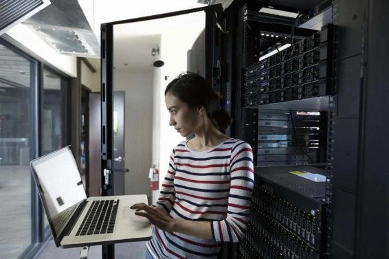 Female filipino it technician working at laptop in server room