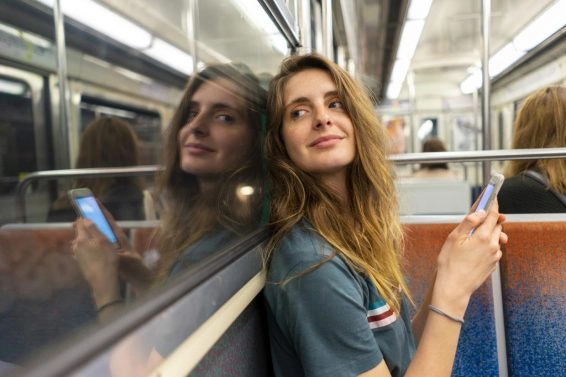 Portrait of smiling young woman and her mirror image in underground train