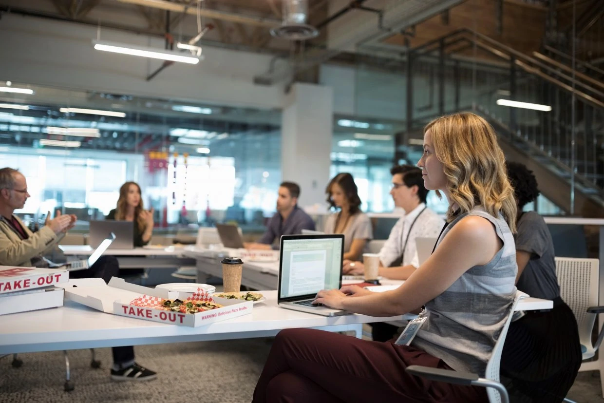 Focused businesswoman using laptop in pizza lunch office meeting