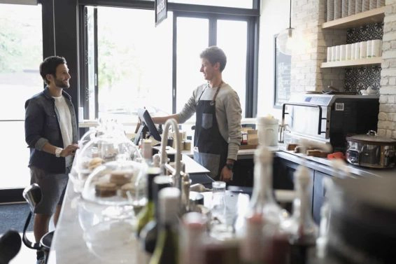 Male customer ordering from worker at cafe counter