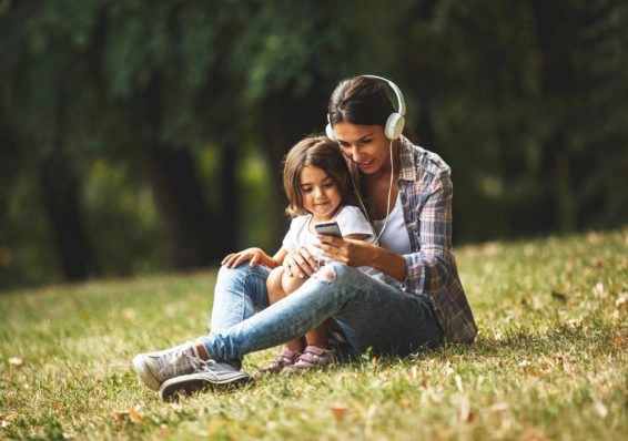 Mother sitting with her daughter and using smartphone