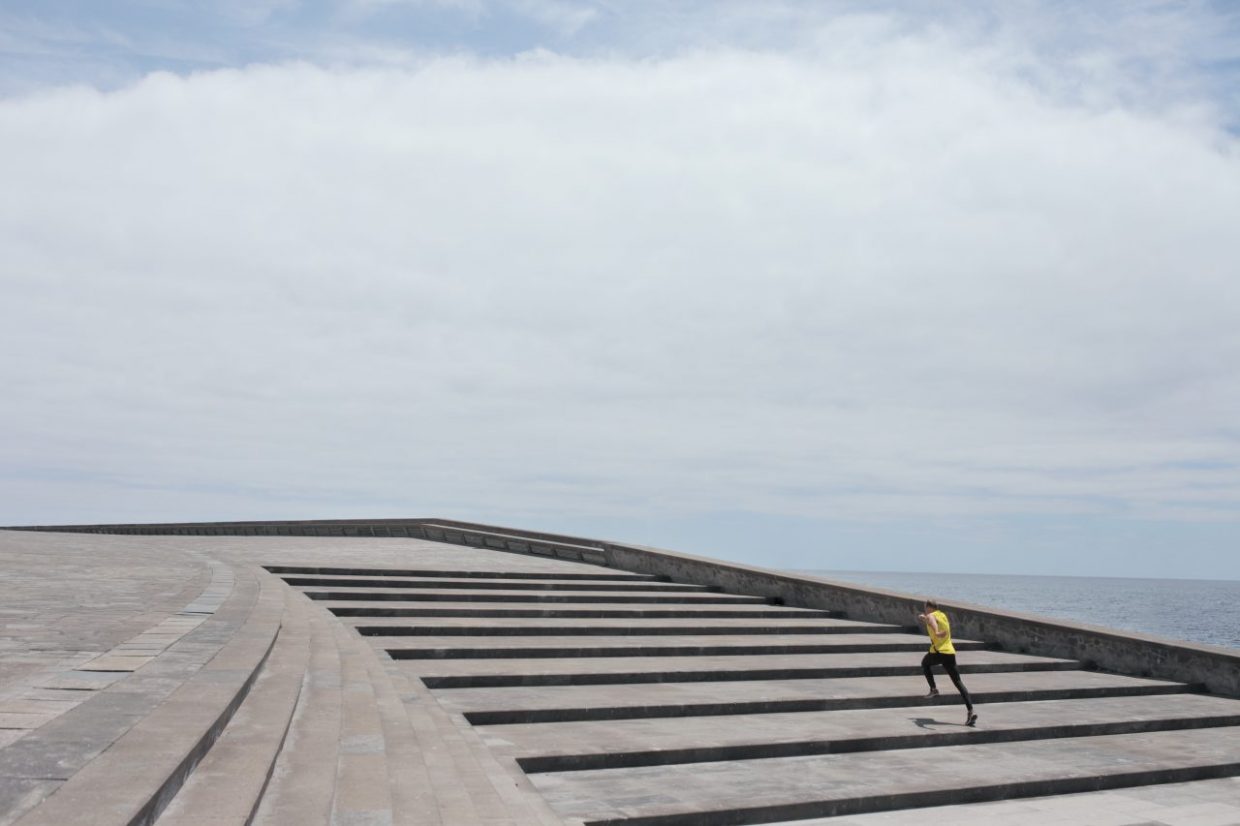 An alone man running up large stairs
