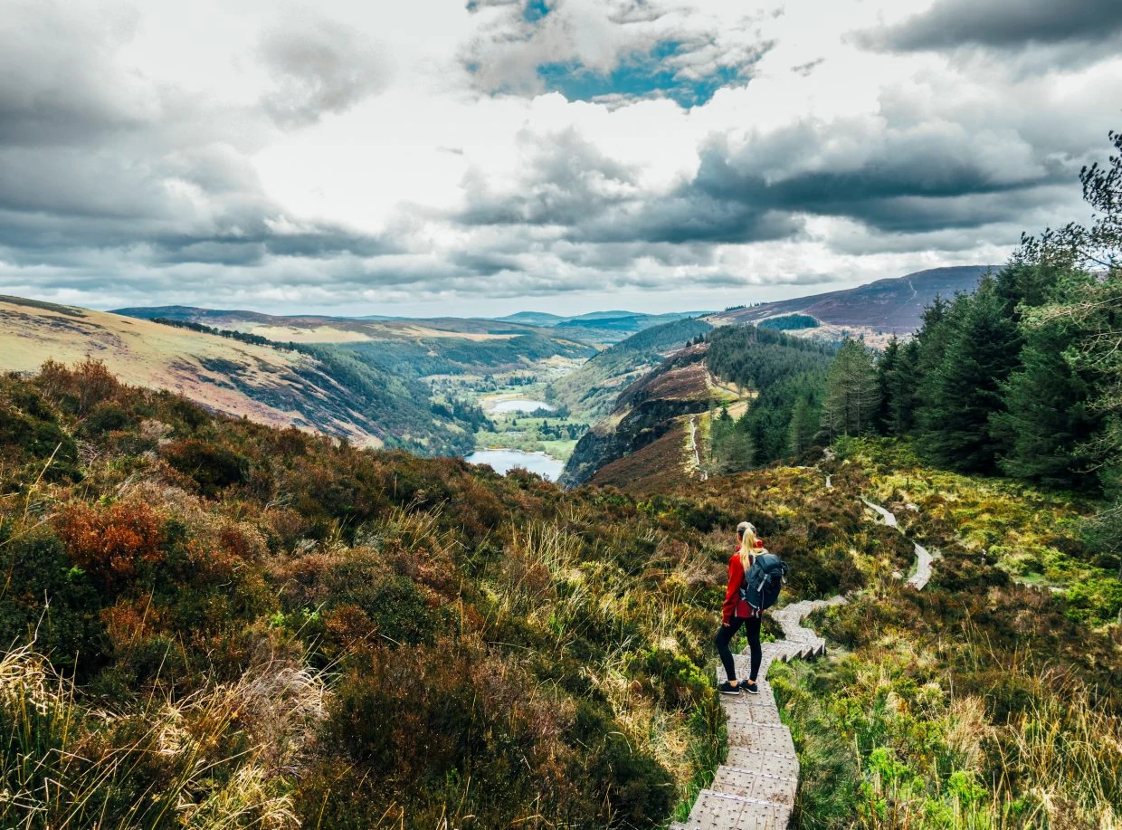 Woman hiking along idyllic mountain path with scenic landscape view, wicklow np, ireland