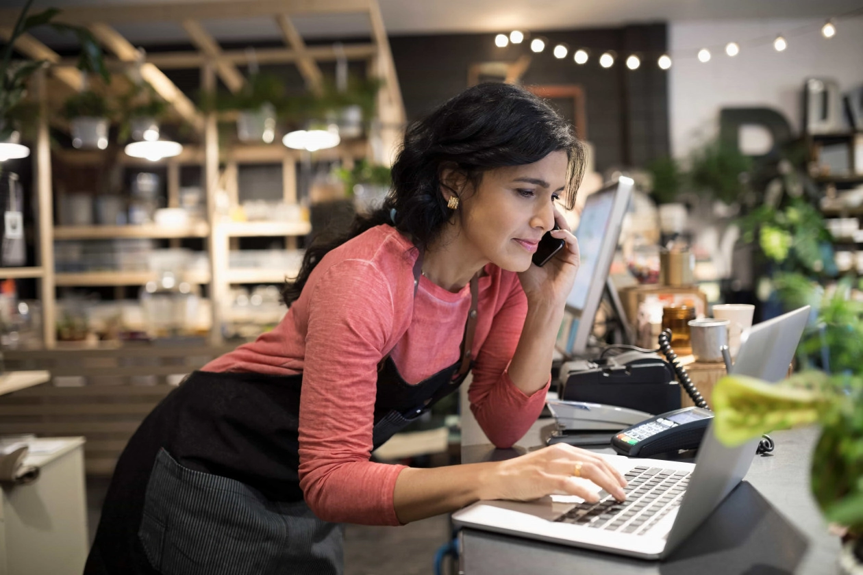 Female shop owner working at laptop at plant shop counter
