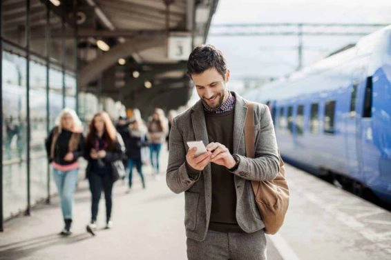 Businessman using mobile phone at train station