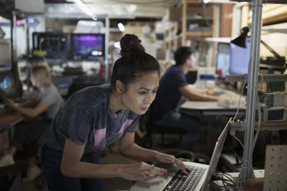 Focused female engineer working at laptop in workshop