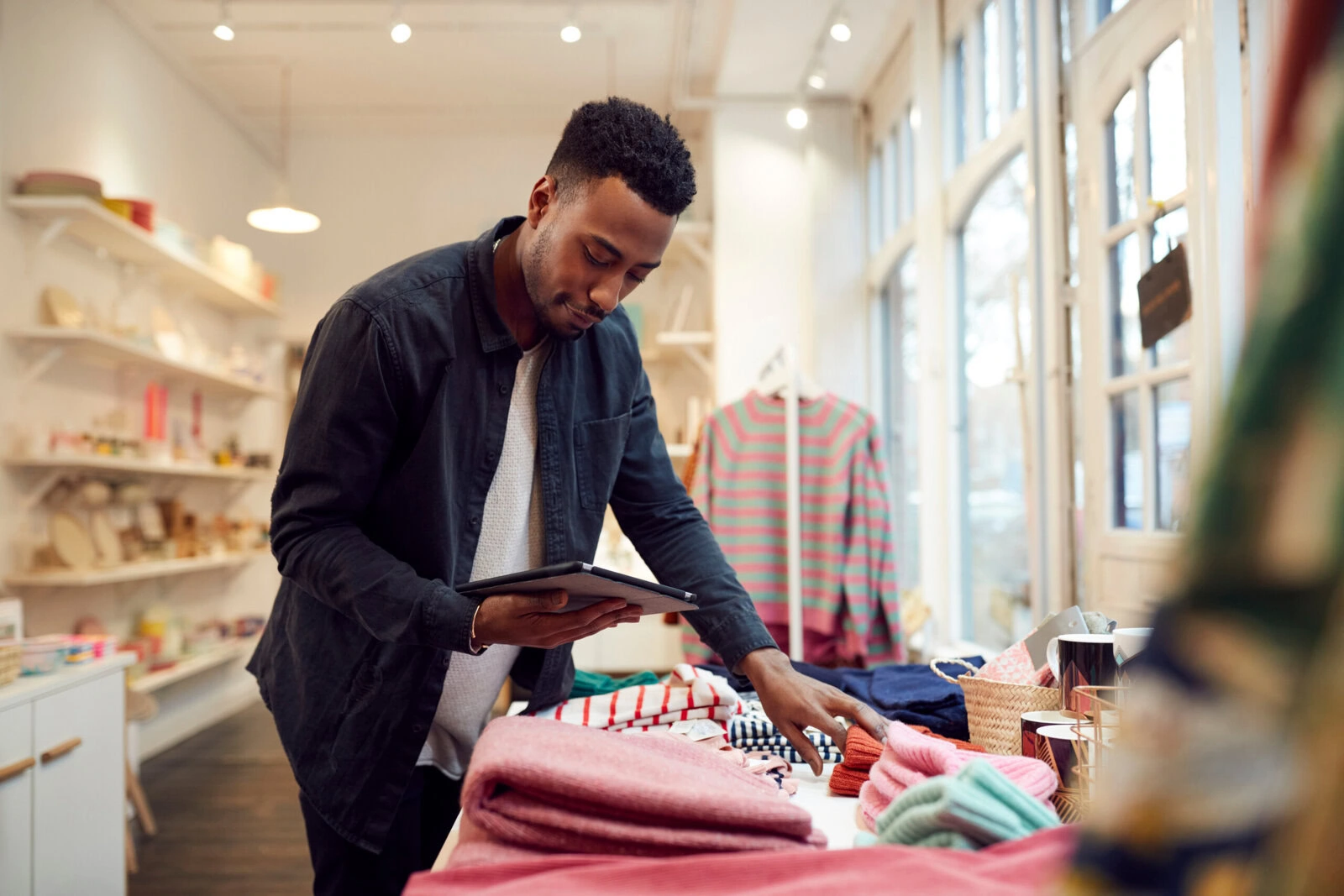 Male small business owner checks stock in shop using digital tablet