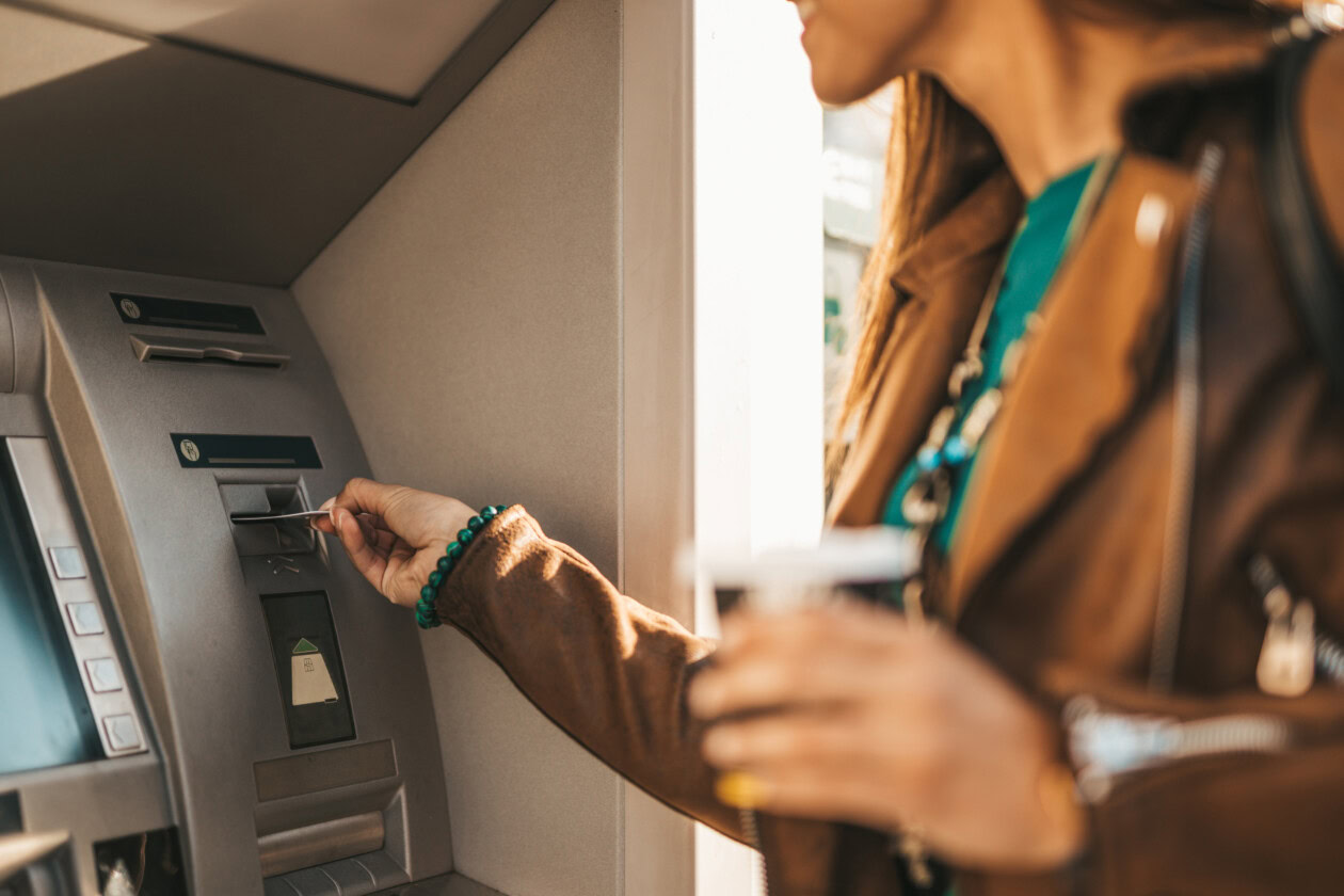 Young woman withdraws money from atm machine.