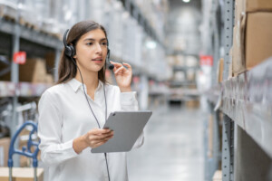 Portrait of warehouse woman staff using digital tablet and talki