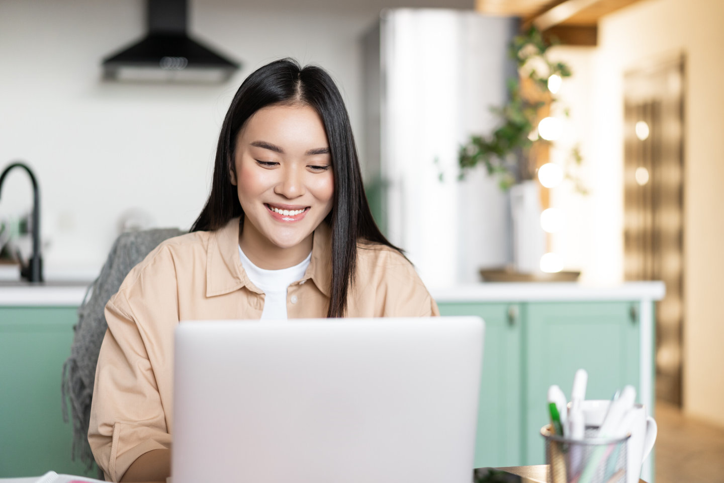 Smiling asian girl using laptop computer, working at home, studying in online school, remote university classes, typing on keyboard jp japan