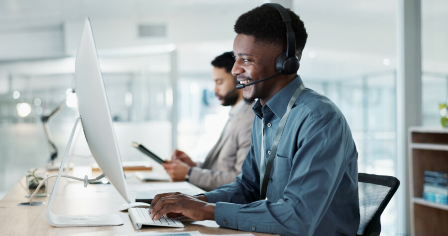Happy black man, call center and customer service in telemarketing, communication or support at office. african male person or consultant agent smile in online advice, help or contact us at workplace