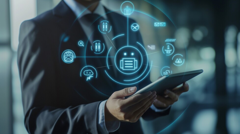 A businessman is utilizing a virtual chatbot on a digital screen for customer support and service. the tablet that the businessman in a suit is holding has an ai robot icon symbol interface on it.