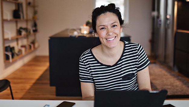 Portrait of smiling mid adult woman using laptop at table in living room