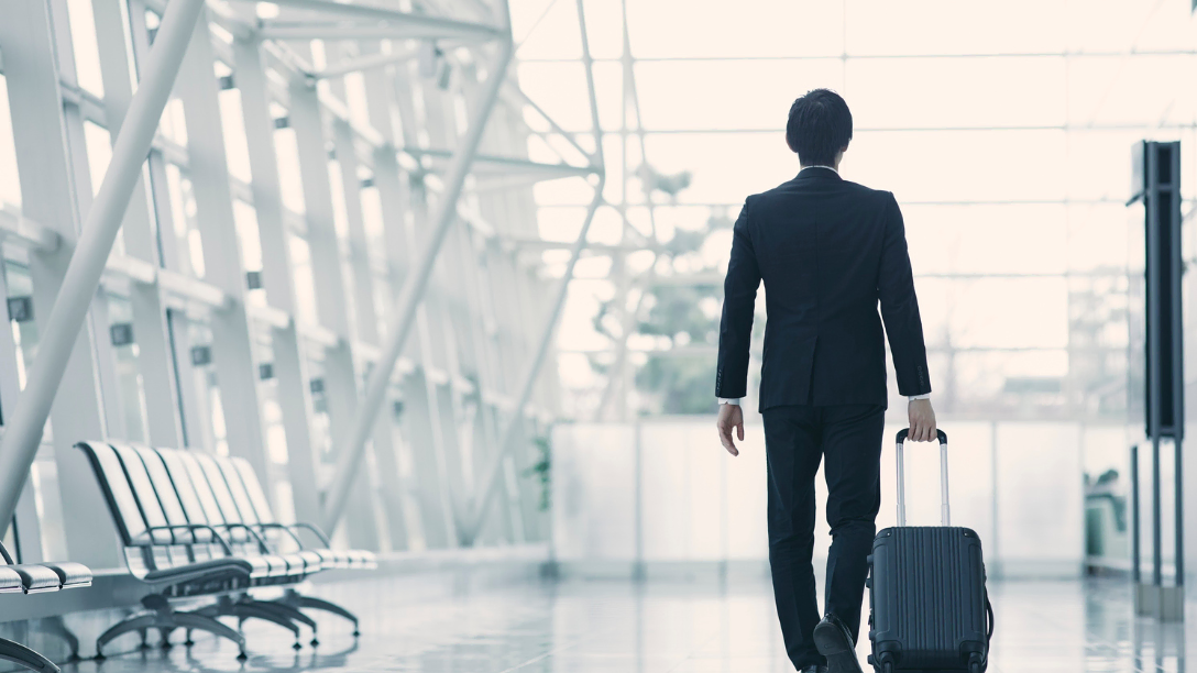 Businessperson walking through airport pulling luggage