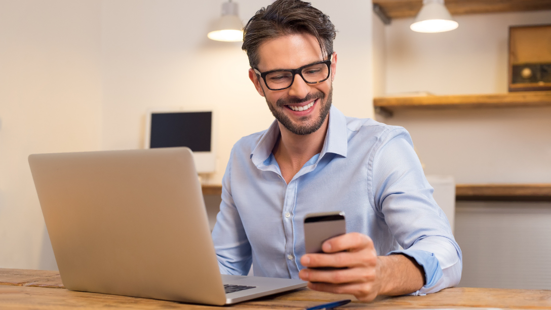 Man using a laptop and phone.