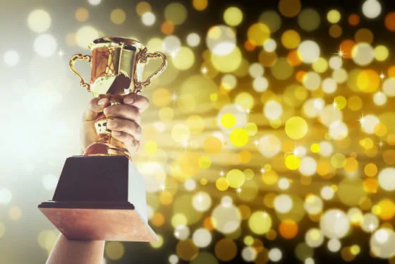 Cropped hand holding trophy against defocused lights