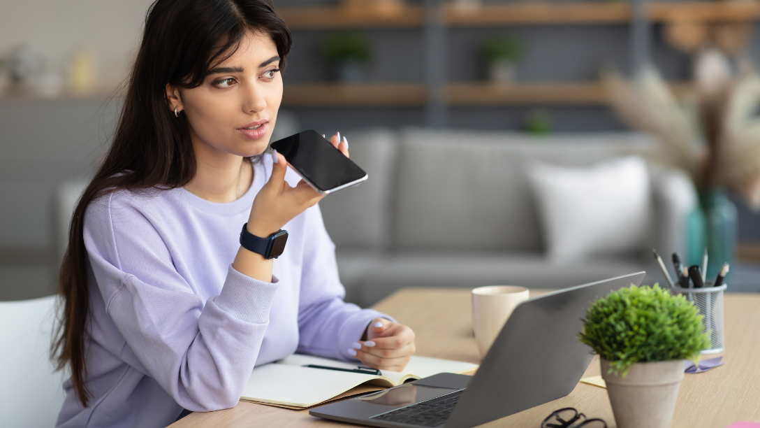 Woman using phone for self service, sitting at laptop