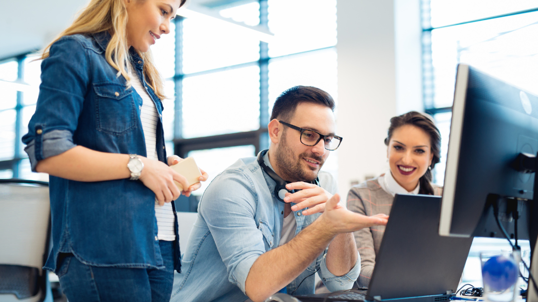 Three colleagues meeting around a laptop.