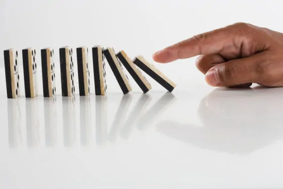 Close up of hand knocking dominos over