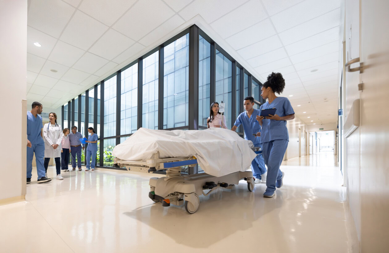 Healthcare workers moving a patient in a gurney at the hospital