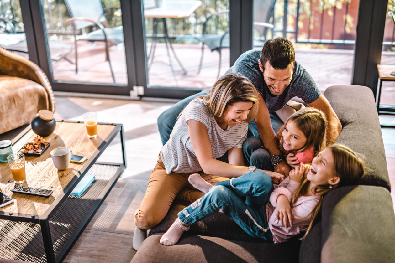 Above view of playful parents tickling their daughters at home.