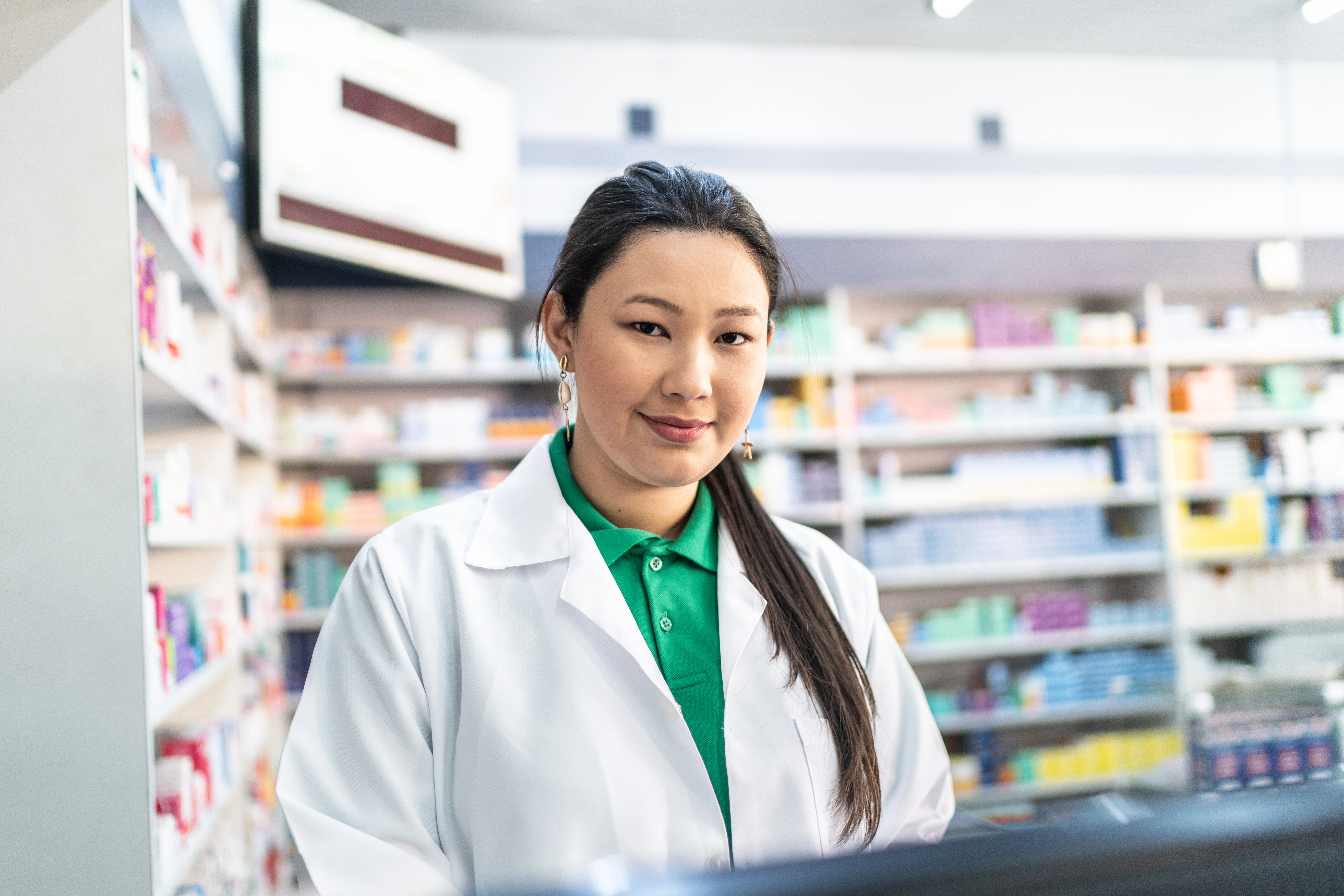 Portrait of young female pharmacist using computer at pharmacy