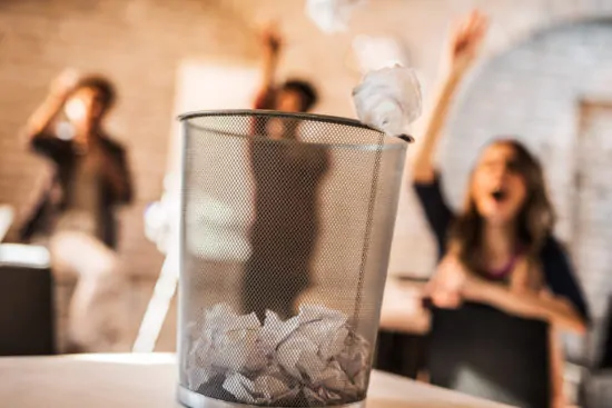 Throwing crumpled paper into a wastepaper basket.