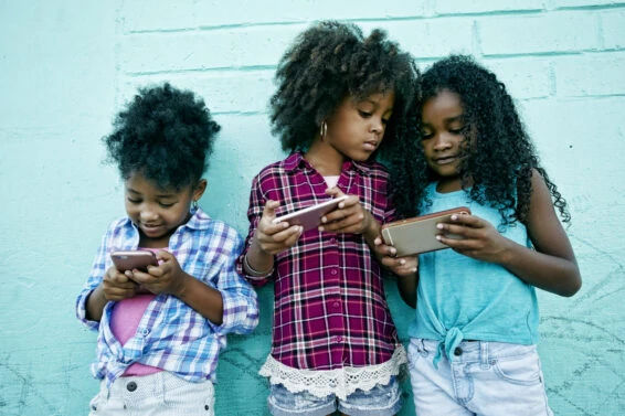 Girls leaning on wall texting on cell phones