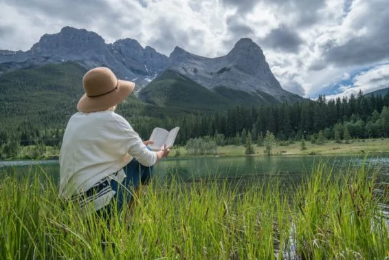 Young woman reading a book by the lake