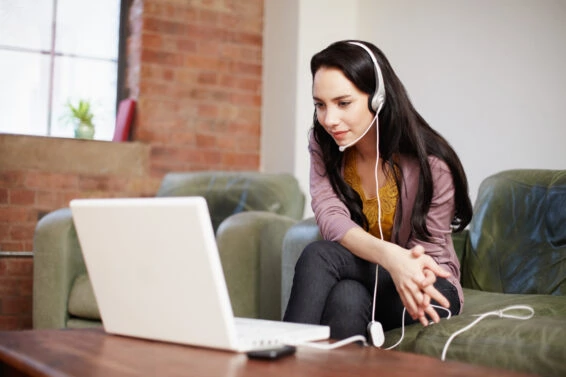 Young woman using voip headset with laptop online