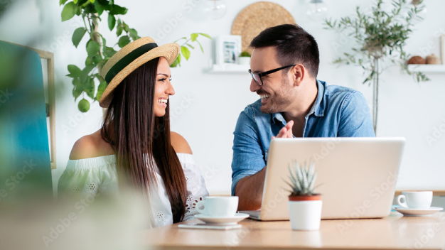 Happy couple drinking coffee and purchasing insurance on their laptop.