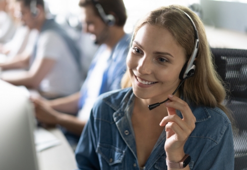 How can I help you Beautiful call center workers in headphones are working at modern office