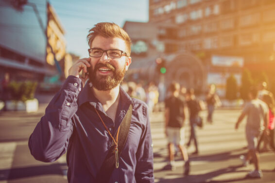 Cheerful businessman using phone in the city street