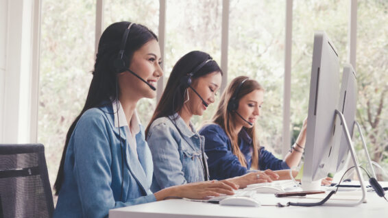 Customer support agent or call center with headset works on desktop computer while supporting the customer on phone call. operator service business representative concept.
