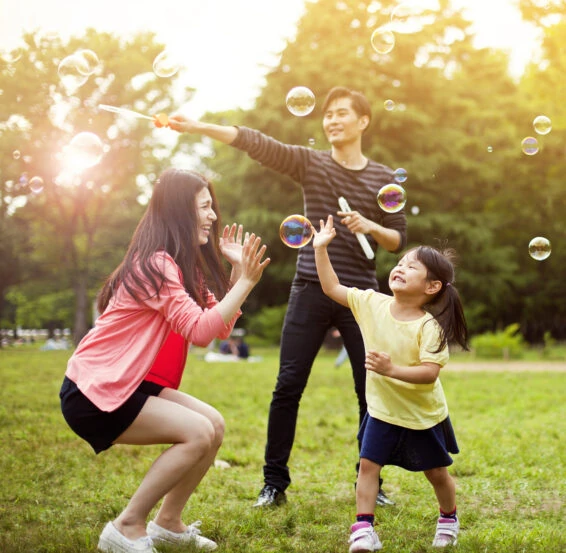 Family having fun in park with soap bubbles