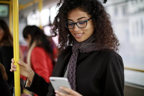 Smiling young woman traveling by bus and using smart phone