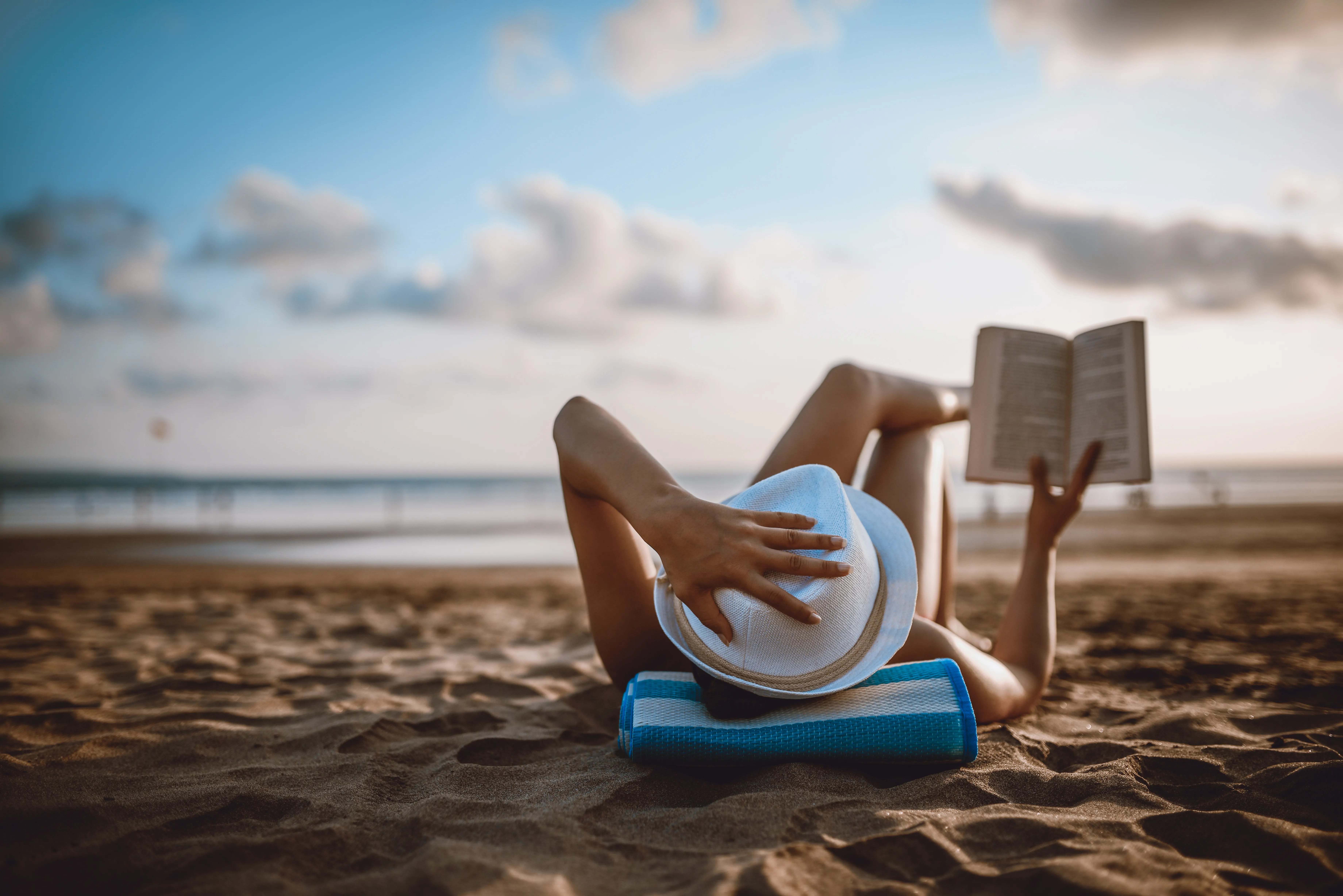 Female reading and enjoying sunset on beach by the ocean