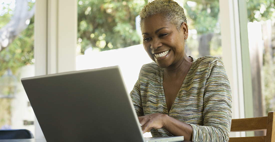 Woman on laptop at a table smiling