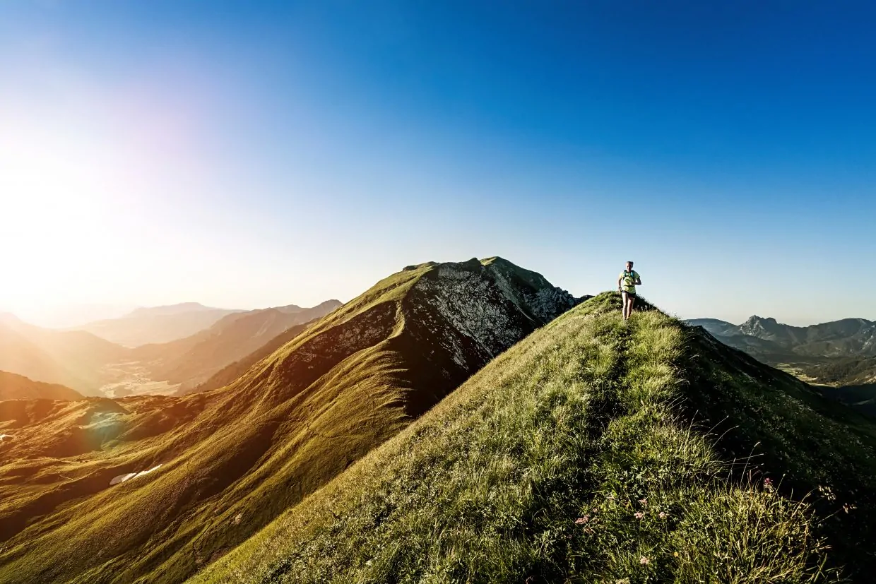 Germany, allgaeu alps, woman running on mountain ridge