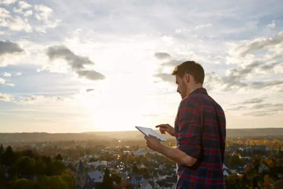 Man using tablet on a hill above a town
