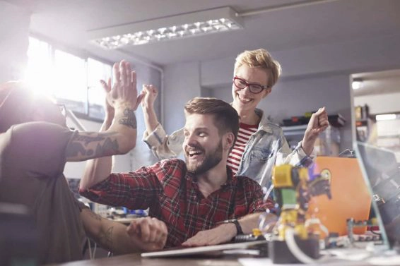 Enthusiastic designers high fiving, celebrating in workshop